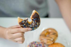 Close up of woman hand holding donuts. Junk food and eating concept. photo