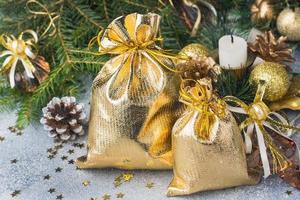 Gold bags with Christmas gifts on the background of Christmas trees and decorations gray background. New year greetings concept. photo