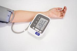 Woman check blood pressure monitor and heart rate monitor with digital pressure gauge with copy space on white background. photo