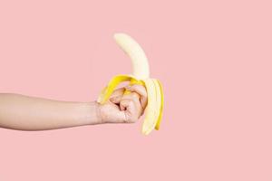 Human hand holding banana fruiton pastel pink background. nutrition concept photo