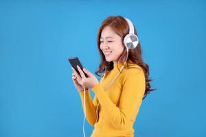 las mujeres hermosas usan ropa informal amarilla. ella escucha música en su teléfono inteligente en el estudio. fondo aislado foto