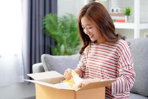 Asian woman smiled and satisfied with the product in the brown box ordered online at home. photo