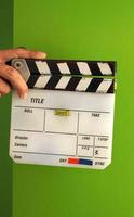 Movie slate board or clapper board and man hand and white color and green screen background in studio. photo