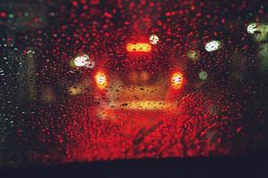 Drops Of Rain Drizzle on the glass windshield in the night. street in the heavy rain. Bokeh Tail light. soft Focus. Please drive carefully, slippery road. traffic jam car. photo