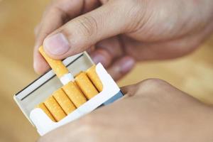 close up man hand holding peel it off cigarette pack prepare smoking a cigarette. Packing line up. photo filters Natural light.