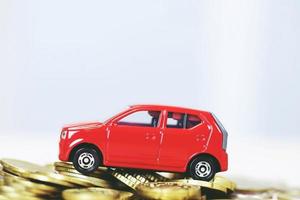 Little red car over a lot of money stacked coins. for  bank loans costs finance. insurance, buying car finance concept. buy and pay by installments down payment a car. photo