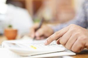 Close up business man hand is writing in a notebook and using calculator counting making notes Accounting at doing finance on desk at office. Savings finances concept. note pad photo