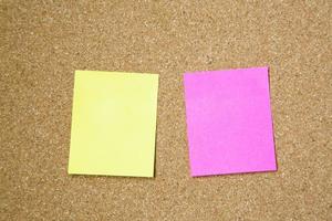 collection of colorful post it two sheets. paper note pad reminder sticky notes on cork bulletin board. empty space for text. office equipment photo