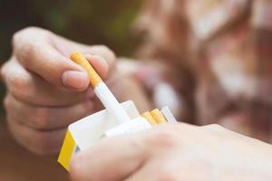 close up man hand holding peel it off cigarette pack prepare smoking a cigarette. Packing line up. photo filters Natural light.