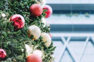 Closeup of red bauble hanging from a decorated christmas tree on blurred of  lights with decorated tree, sparkling and bokeh background. copy space for your text. photo