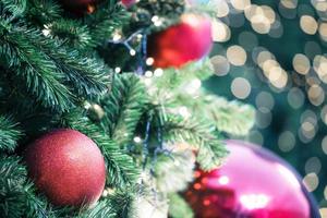 Closeup of red bauble hanging from a decorated christmas tree on blurred of  lights with decorated tree, sparkling and bokeh background. copy space for your text. photo