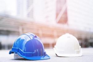 sombrero de casco de seguridad duro azul y blanco en el proyecto en el edificio del sitio de construcción en el piso de concreto en la ciudad. casco para obrero como ingeniero o trabajador. concepto seguridad primero