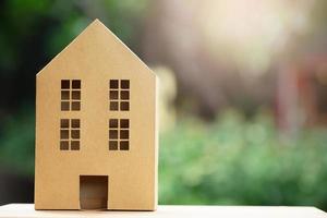 home in brown recycled paper model  set many backs on wooden table in Garden Morning sunlight background. Eco friendly house. photo