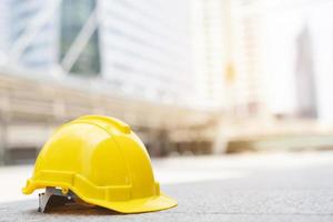 sombrero de casco de seguridad duro amarillo en el proyecto en el edificio del sitio de construcción en el piso de concreto en la ciudad con luz solar. casco para obrero como ingeniero o trabajador. concepto de seguridad primero.