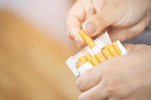 close up man hand holding peel it off cigarette pack prepare smoking a cigarette. Packing line up. photo filters Natural light.