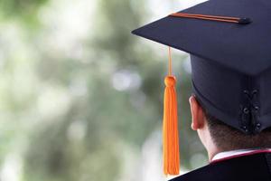 toma de sombreros de graduación masculinos jóvenes en la parte trasera durante el éxito del comienzo, educación conceptual felicitar al graduado en la universidad al aire libre. foto