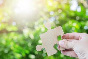 hands person trying to connect couple Jigsaw wooden puzzle piece with tree fresh background. one part of whole. symbol of association and connection. success and business solution strategy photo