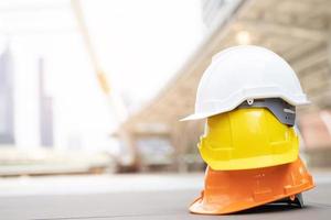 sombrero de casco de seguridad duro amarillo y blanco en el proyecto en el edificio del sitio de construcción en el piso de concreto en la ciudad con luz solar. casco para obrero como ingeniero o trabajador. concepto de seguridad primero.