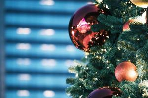 Closeup of red bauble hanging from a decorated christmas tree on blurred of  lights with decorated tree, sparkling and bokeh background. copy space for your text. photo