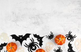 vista superior sobre calabazas de halloween, murciélagos, arañas y calaveras sobre fondo de hormigón. celebración del 31 de octubre. banner con lugar para texto foto