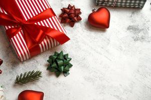 Top view on gift box in red paper with bows and ornaments near on concrete background. Flat lay with place for text photo