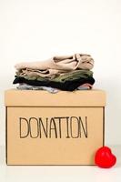 Vertical banner.Closeup of donation box with stack of clothes near.Charity concept photo