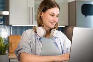 Closeup of a smilig female using laptop.Student writing lecture or woman works from home photo