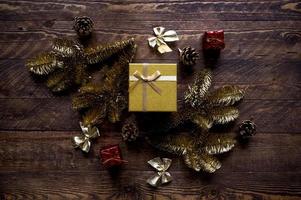 el piso de navidad vintage yacía en colores dorados y rojos. caja de regalo brillante rodeada de elementos de decoración y ramas de abeto pintadas en oro