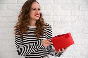 Valentine's day concept with young smiling girl holding red gift box.Women's day photo