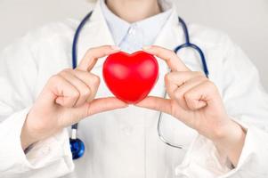 médico irreconocible sosteniendo el corazón en la mesa. donaciones de órganos, caridad, concepto de cardiología foto