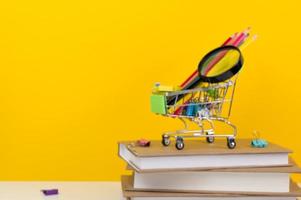 Education, Back to School. Shopping cart with supplies near pile of books.Defocused image photo