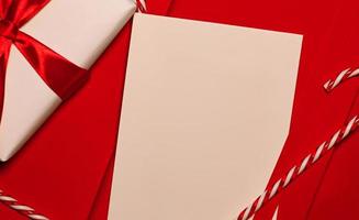 Mockup woth red notebook,gift and candy canes against red background photo