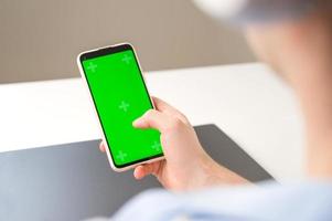 Un recognizable man using Smartphone with Green Chroma Key Screen. Mockup. Modern tecnologies,online shopping,social media applications etc photo