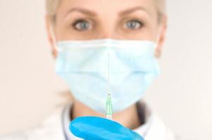 Side view medical worker wearing mask holding syringe.Vaccination concept.Selective focus on syringe photo