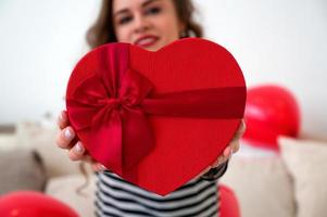 Close up of woman hold gift box red heart for Valentines Day.Delivery present.Suprise photo