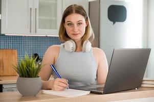 Closeup of a female student smiling and holding pen near laptop.Back to school concept photo