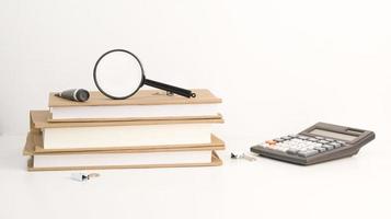 Stack of books with magnifier on top and calculator near. Back to school. photo