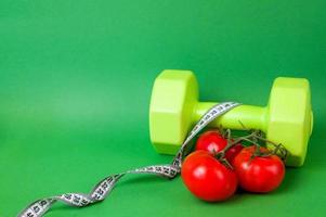 Side view of dumbbell against green background near measring tape. Workouts and sport concept. Healthy lifestyle.Vegetables photo