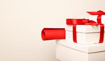 Stack of white gifts with red bows and red wrapping paper against white background. Copyspace.Christmas photo