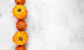 Thanskgiving flat lay with yellow and orange pumpkins on left side against white background. Template.Copyspace banner photo