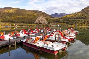 Kaltern, South Tyrol, Italy -14 November 2022 Pedal boats in natural bathing lake Caldaro in autumn photo