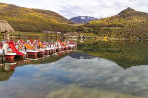 Kaltern, South Tyrol, Italy -14 November 2022 Pedal boats in natural bathing lake Caldaro in autumn photo