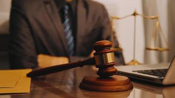 Justice and law concept.Male judge in a courtroom with the gavel, working with, computer and docking keyboard, eyeglasses, on table in morning light video