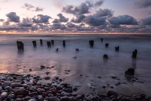 costa del mar báltico con guijarros y hielo al atardecer foto