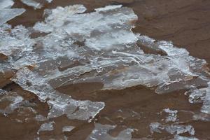 costa del mar báltico con guijarros y hielo al atardecer foto