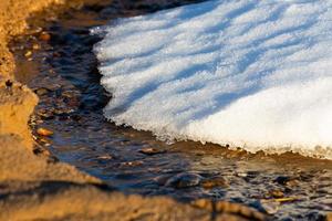 costa del mar báltico con guijarros y hielo al atardecer foto