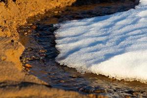 costa del mar báltico con guijarros y hielo al atardecer foto