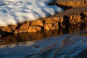 costa del mar báltico con guijarros y hielo al atardecer foto