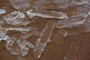 costa del mar báltico con guijarros y hielo al atardecer foto