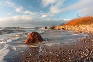 costa del mar báltico con guijarros y hielo al atardecer foto